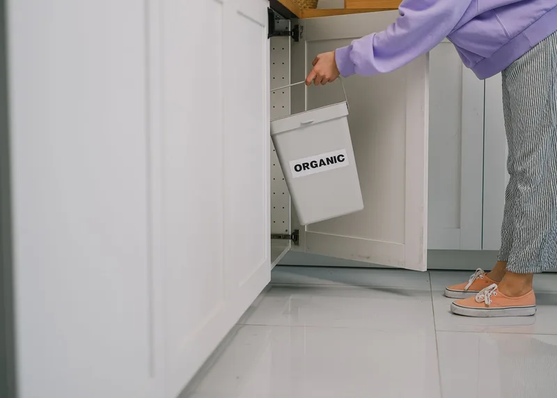 Eine Person stellt einen Bioabfallbehälter in einen Küchenschrank